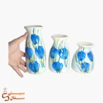 گلدان رومیزی آبی ست ۳ تایی مدل نسیم با گل‌های آبی روی زمینه‌ی سفید درکنار دست