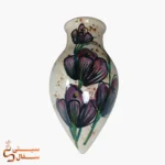 گلدان دیوارکوب قطره‌ای بنفش مدل شبنم سرامیکی با گل‌های بنفش و خط‌دور مشکی روی زمینه‌ی کرم